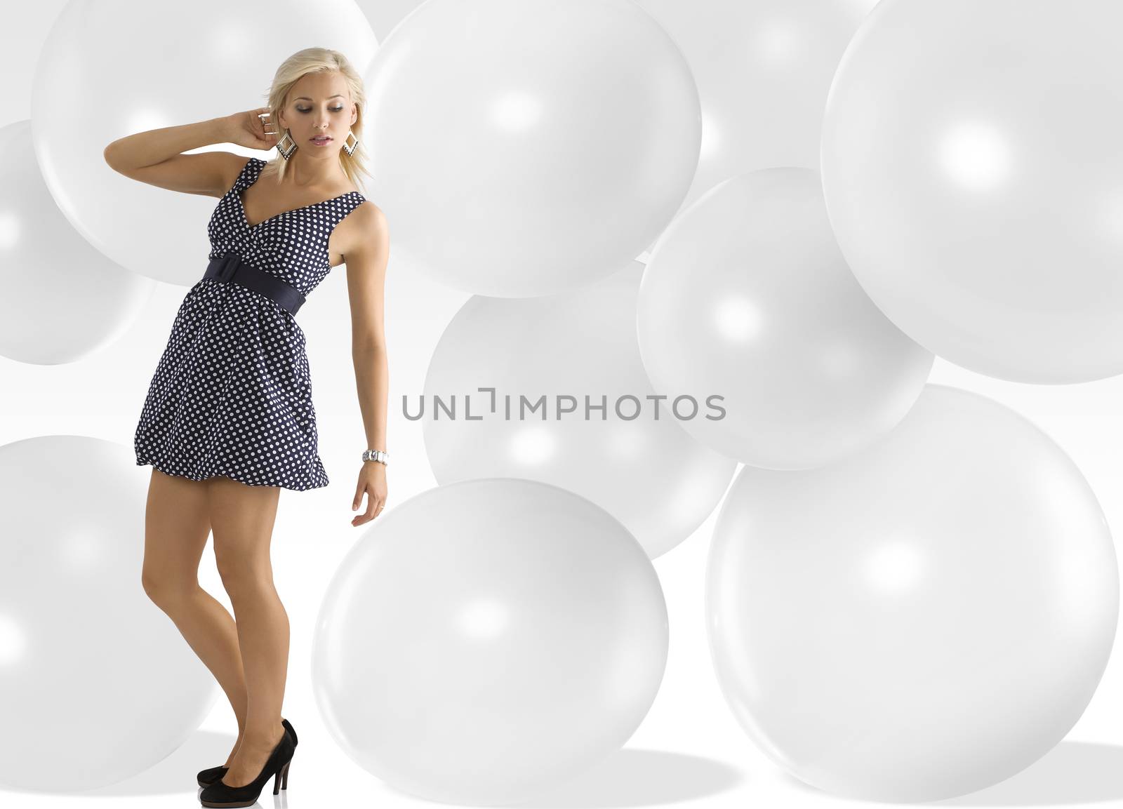 blond young woman wearing blue polka dot dress jewellery and taking pose