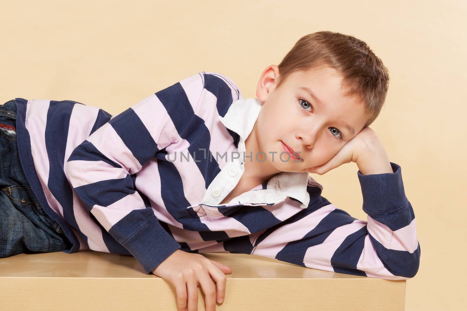Young model boy lying on table and looking into camera. Youth fashion concept.