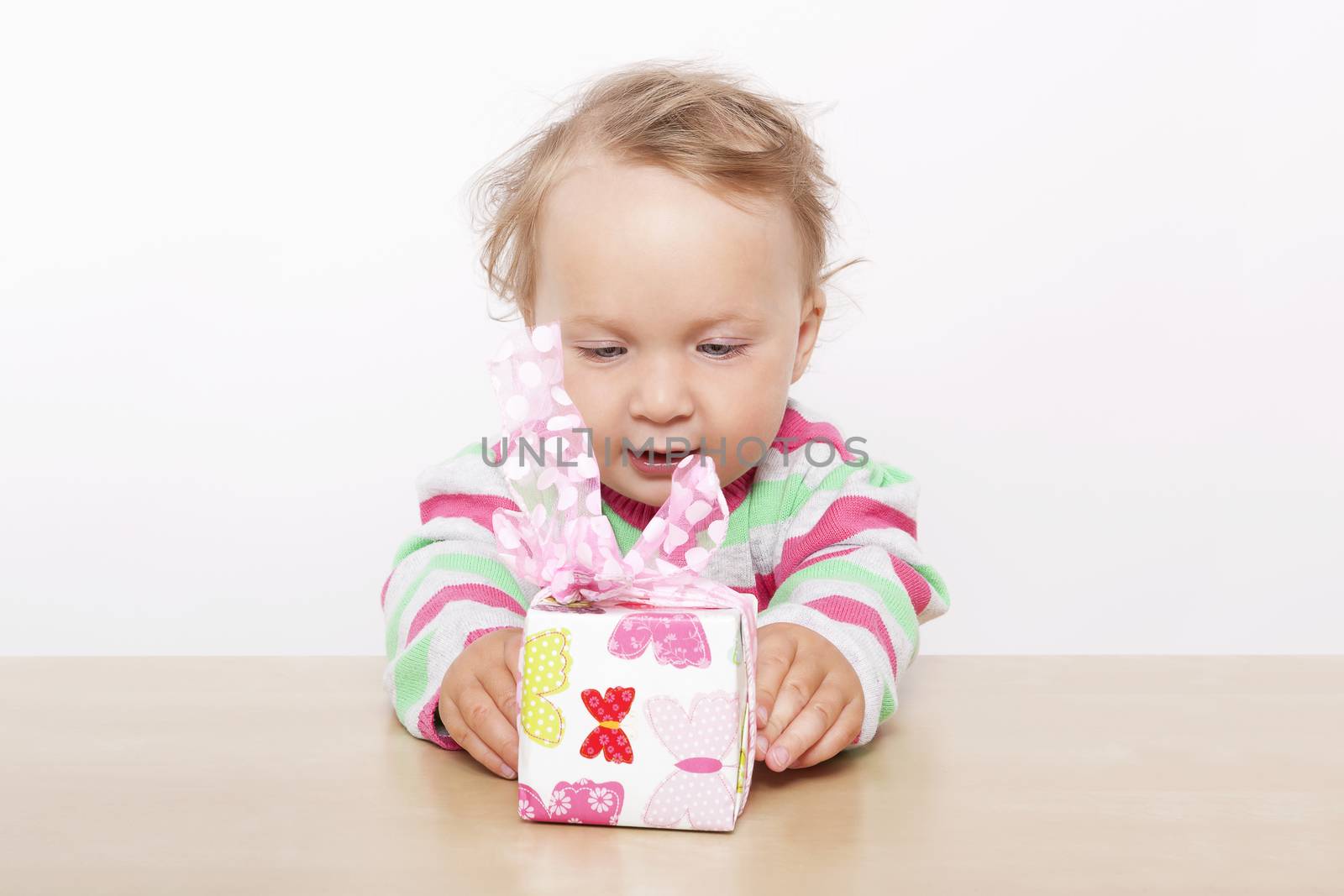 Birthday surprise. Cute baby girl opening present isolated on white background. 