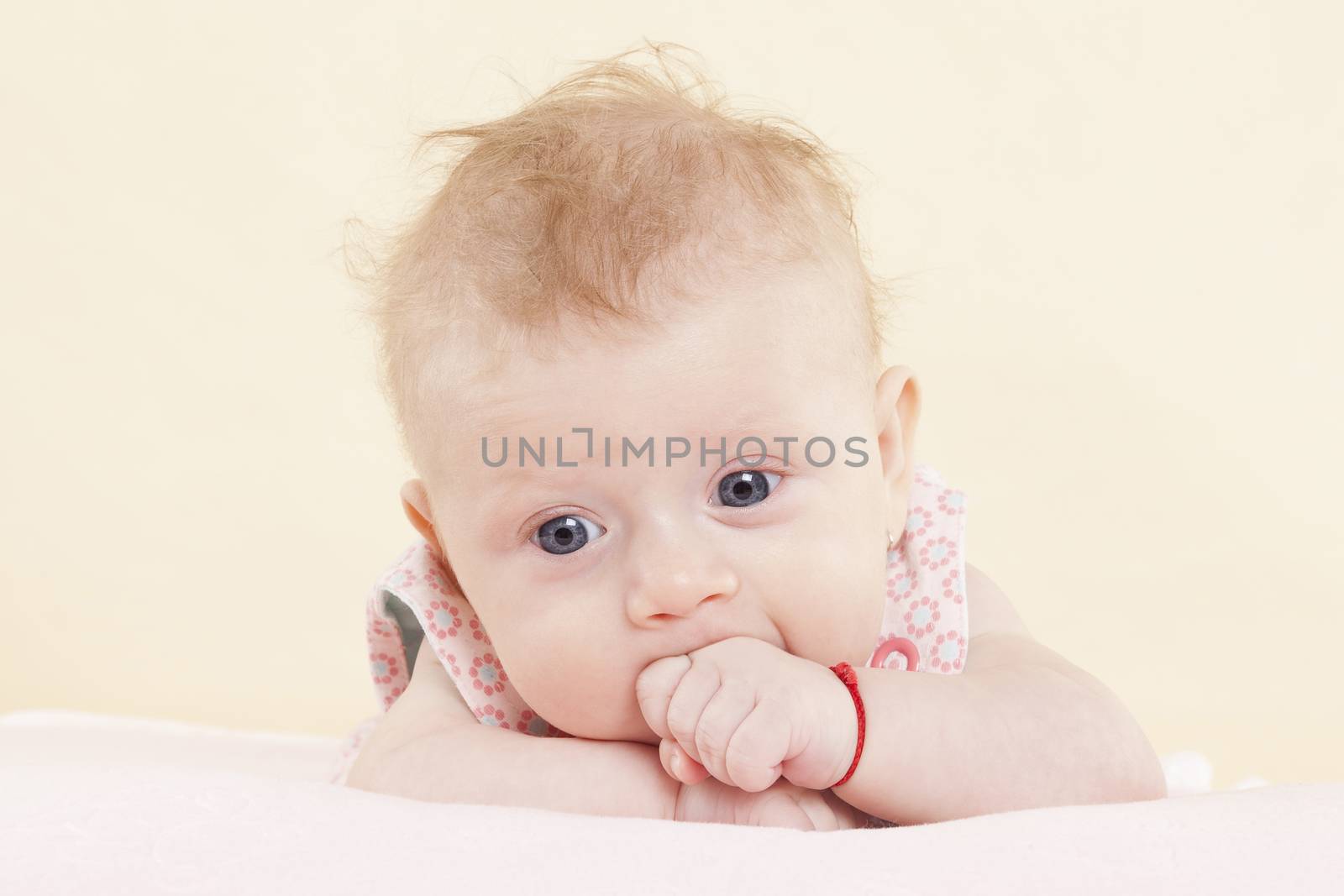 Baby girl with big blue eyes and fist in mouth portrait. Cute newborn concept.