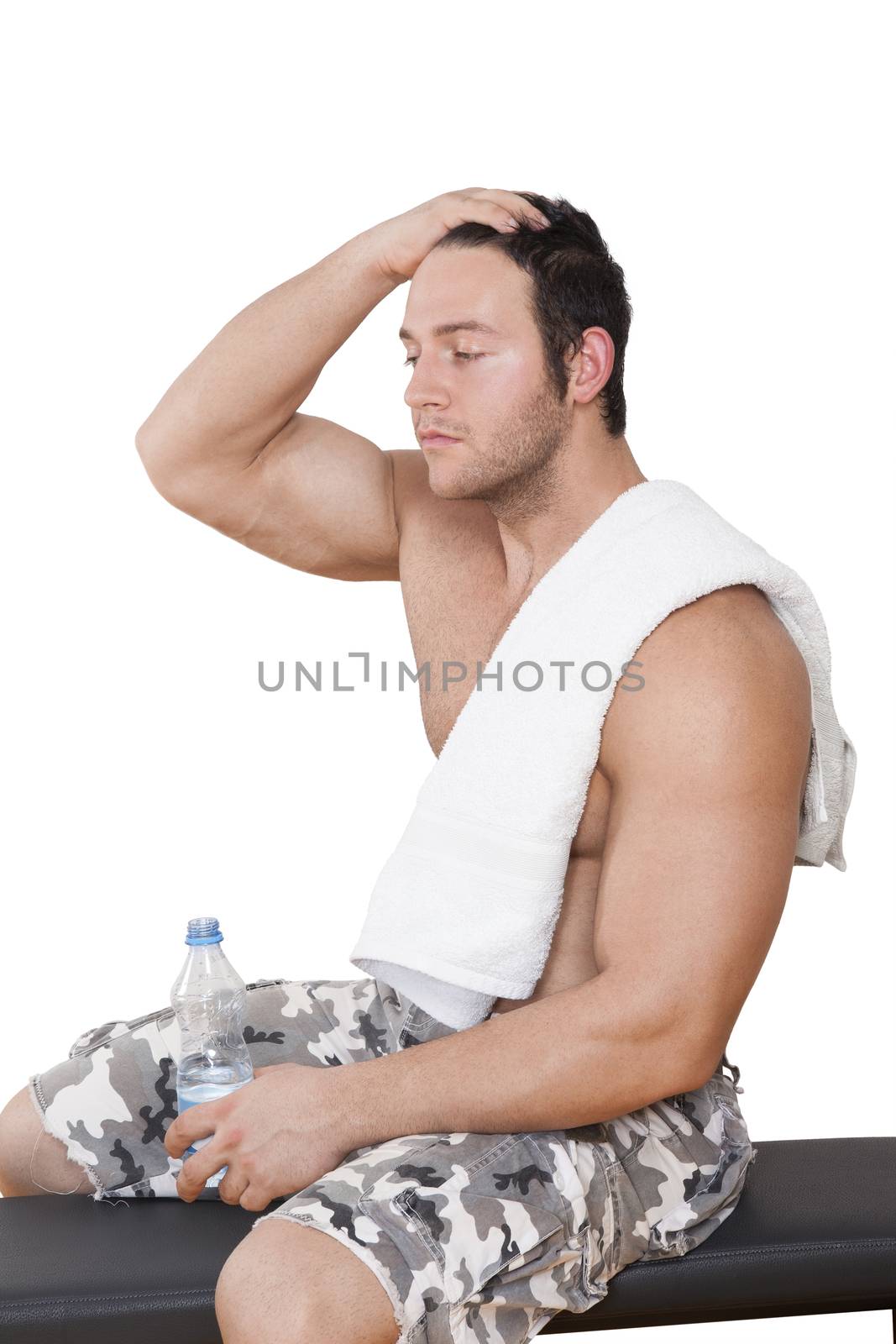 Bodybuilder resting after workout sitting on bench with water and towel isolated on white background. Sport, Fitness and Health.