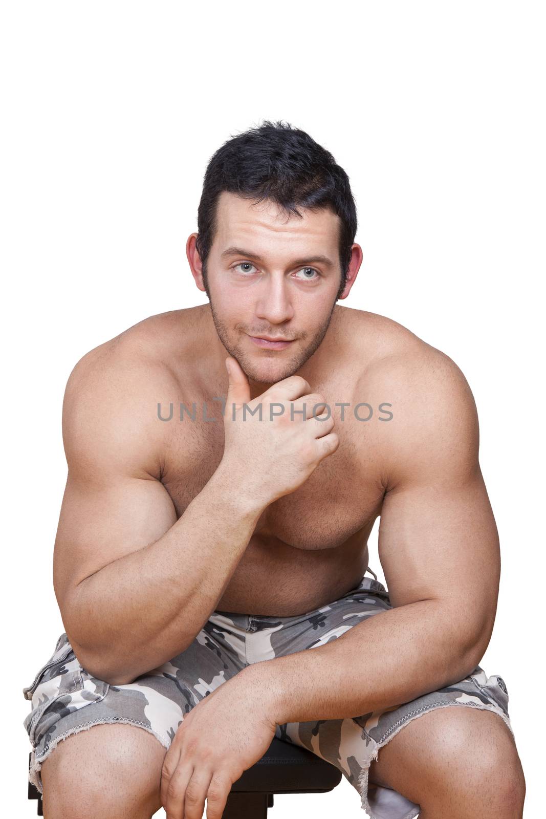 Sexy muscular shirtless athlete sitting, touching chin and looking into camera isolated on white background. Fitness, sport and health background.