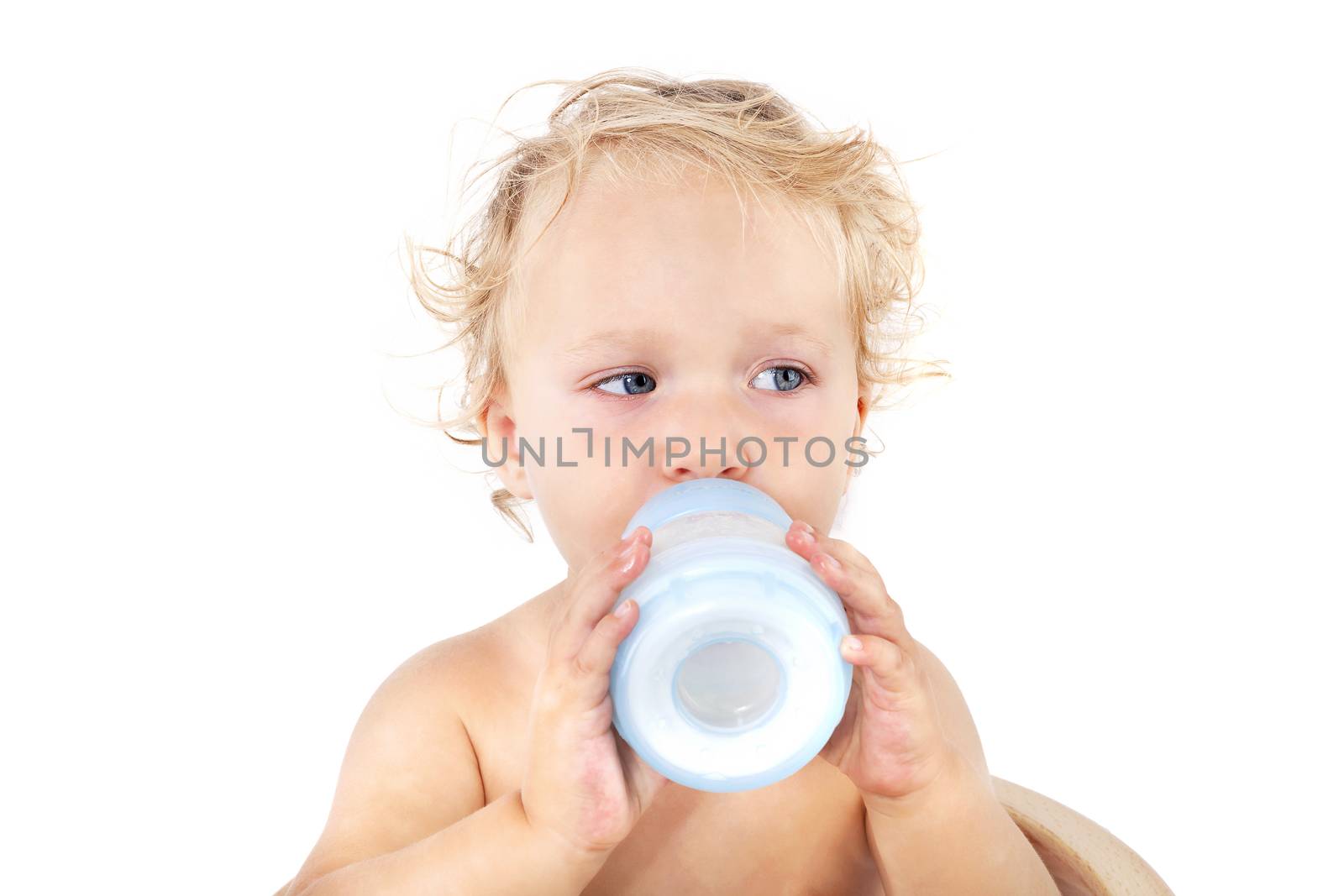 Cute blonde curly baby girl drinking milk from baby battle isolated on white background. Baby, milk and eating concept with copy space.