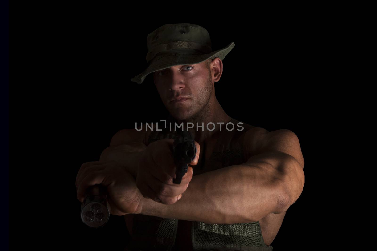 Muscular soldier aiming the gun on the camera, isolated on black background. Proud, serious special forces soldier. Army and Military,