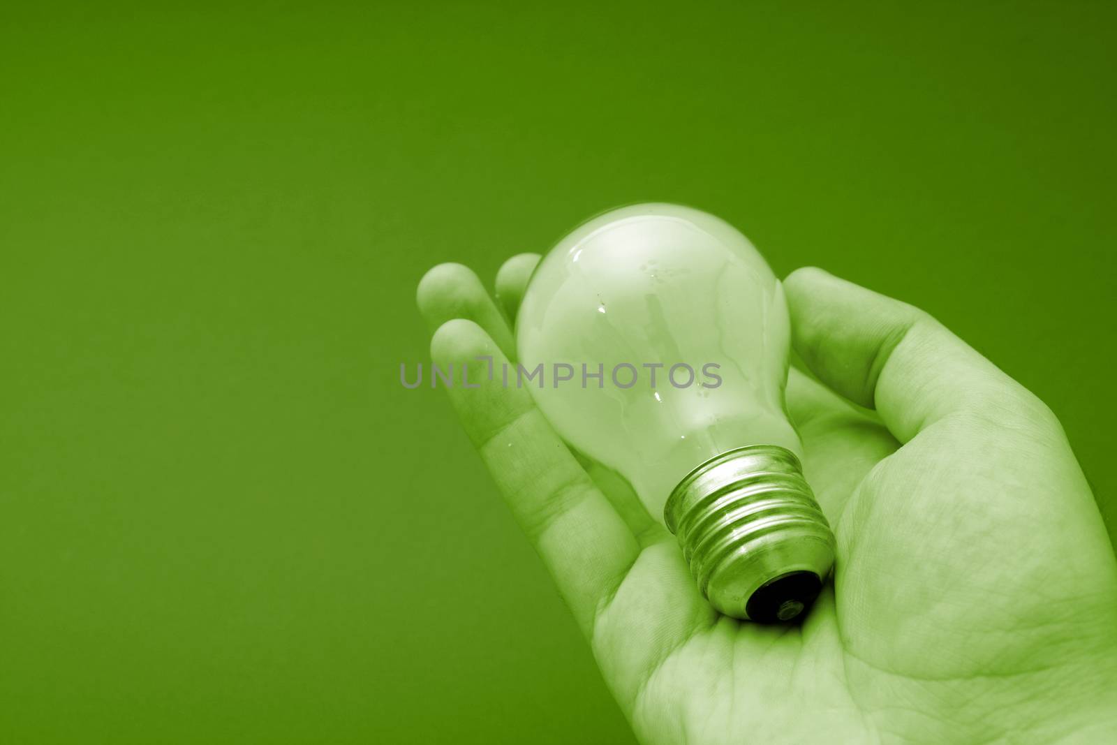 Background with lit lightbulb. Isolated on green.