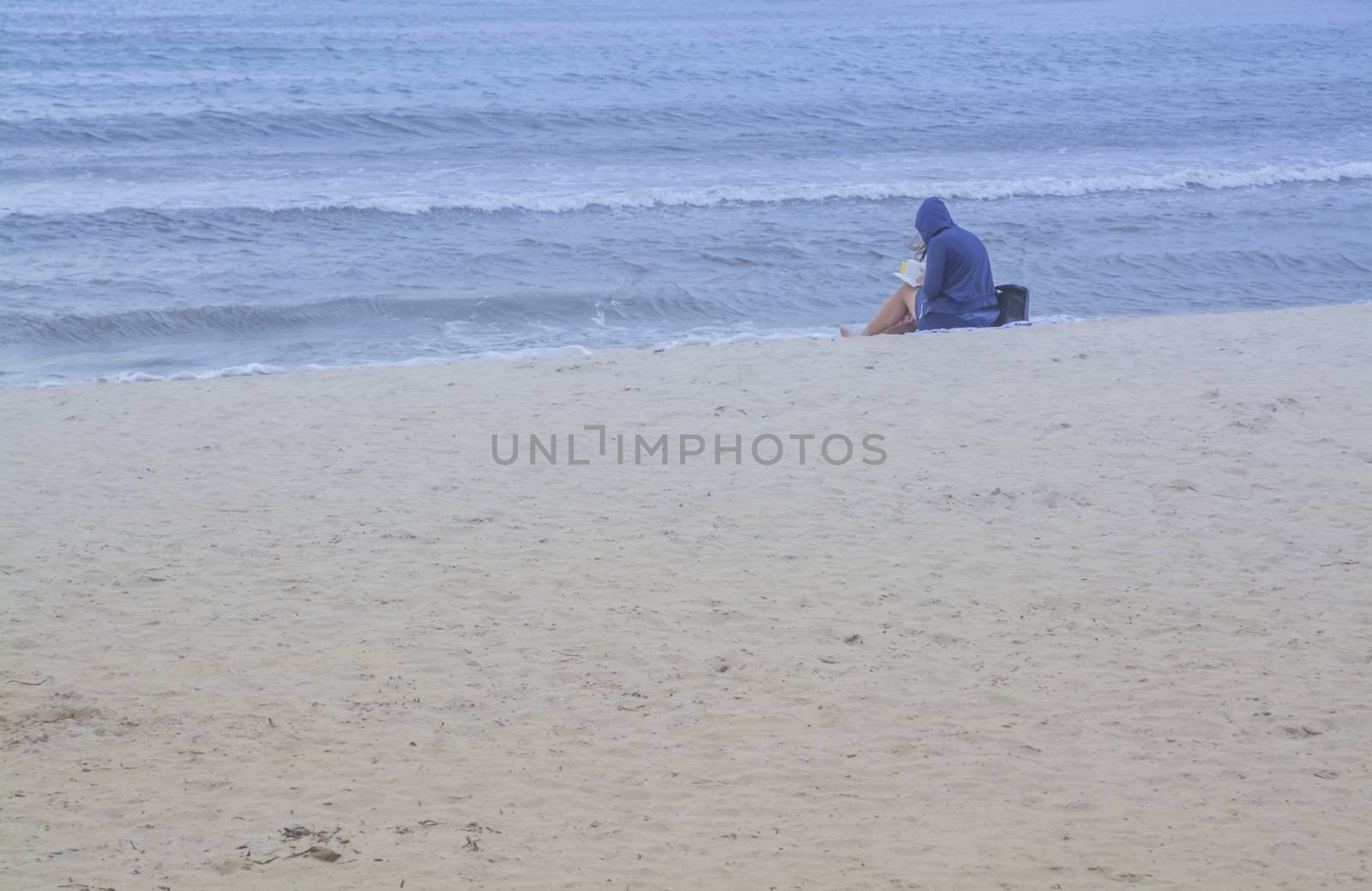 Young woman reading on sandy beach. by ArtesiaWells