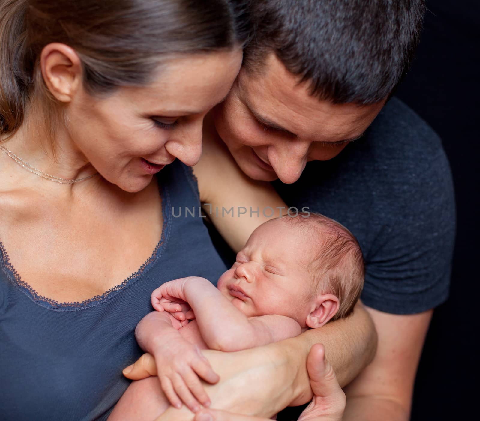 Beautiful mother and father smiling holding their newborn baby boy