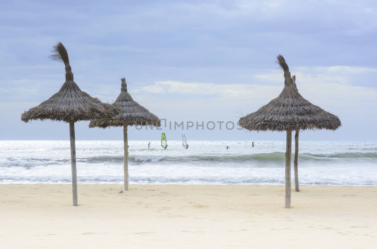 Windsurfers and parasols in Playa de Palma, November. Mallorca, Balearic islands, Spain.