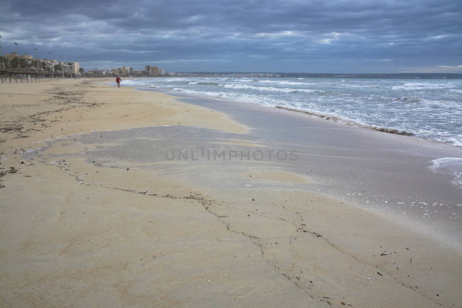 Man walking with football on the beach. Sandy beach and storm waves in November, Mallorca, Balearic islands, Spain.