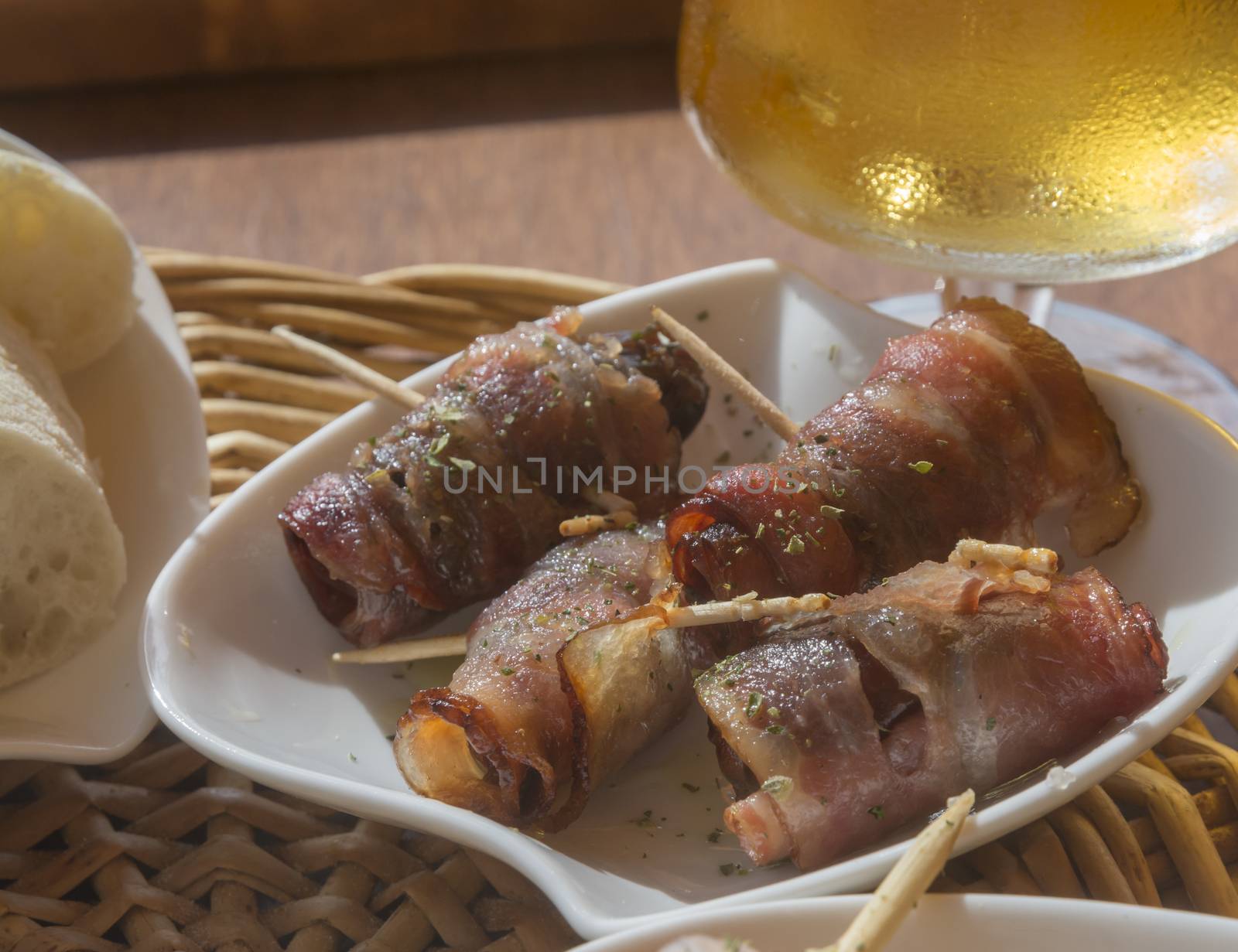 Bacon date tapas. Tapas with dates rolled in bacon and beer on a restaurant table. Mallorca, Balearic islands, Spain.