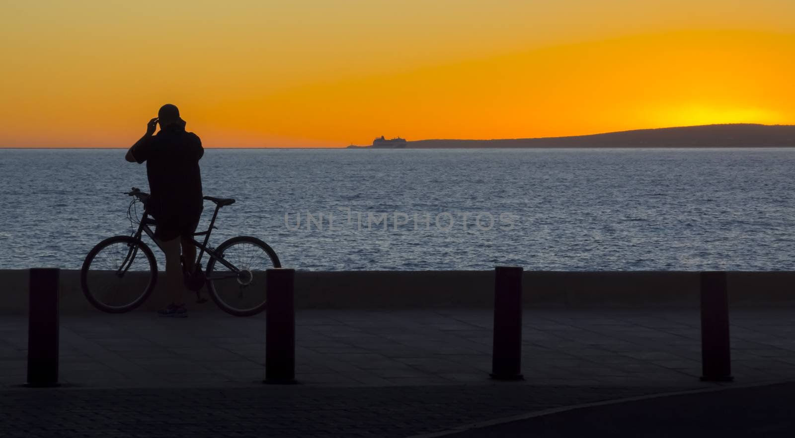 Bicyclist Sunset. Bicyclist watching sunset in Cala Estancia, Mallorca, Balearic islands, Spain in October.