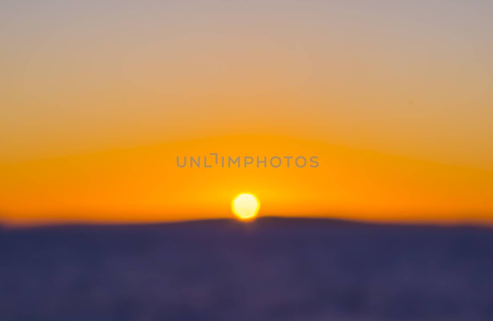 Colorful Sunset Blur , expressionistic style, with centered setting sun on blue or purple earth, water and yellow sky. Mediterranean, Mallorca, Balearic islands, Spain.