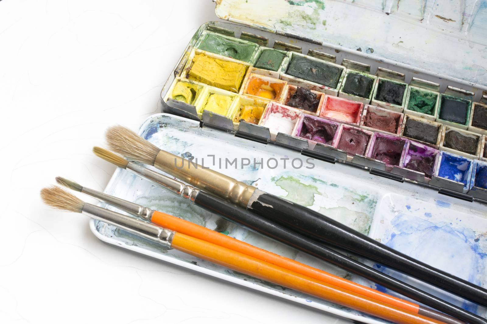 Watercolor box. Artist tools - a well used and messy watercolor box and brushes.