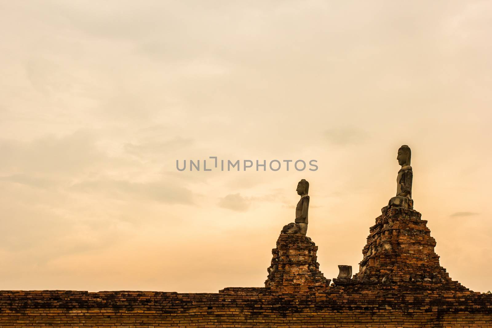 Buddha statue on sunset sky background by kannapon