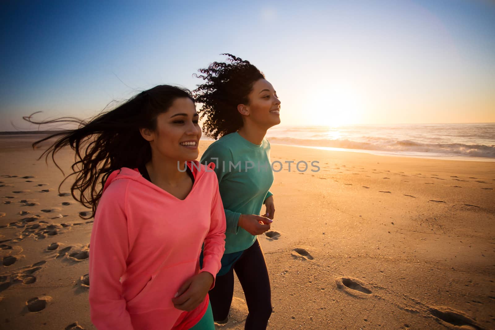 Couple of women running and walking on the beach