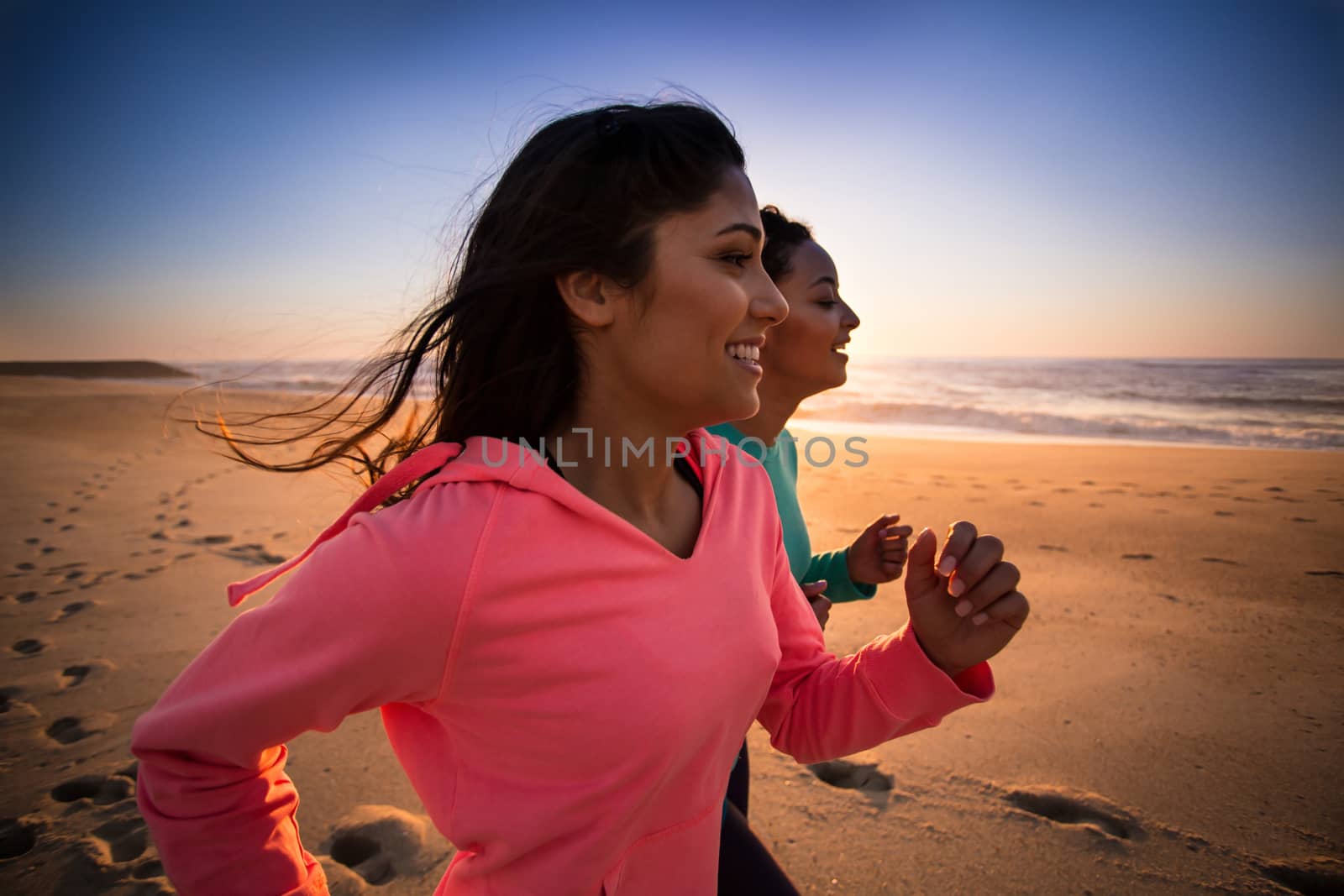 Couple of women running and walking on the beach