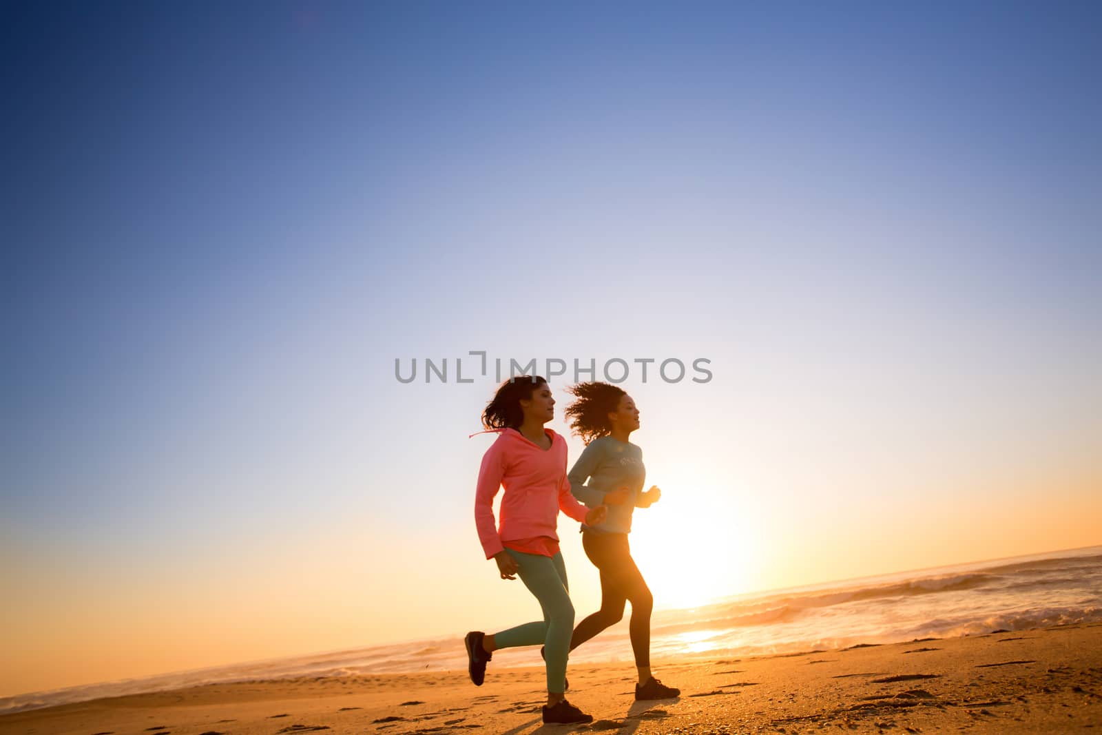 Couple of women running and walking on the beach