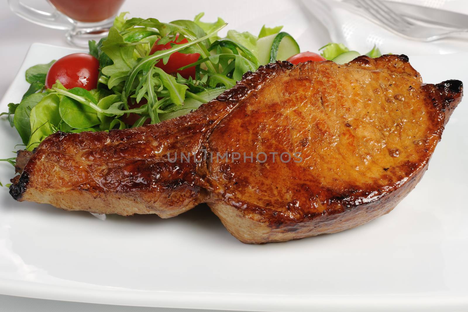 Fried steak on the bone with vegetables and ketchup