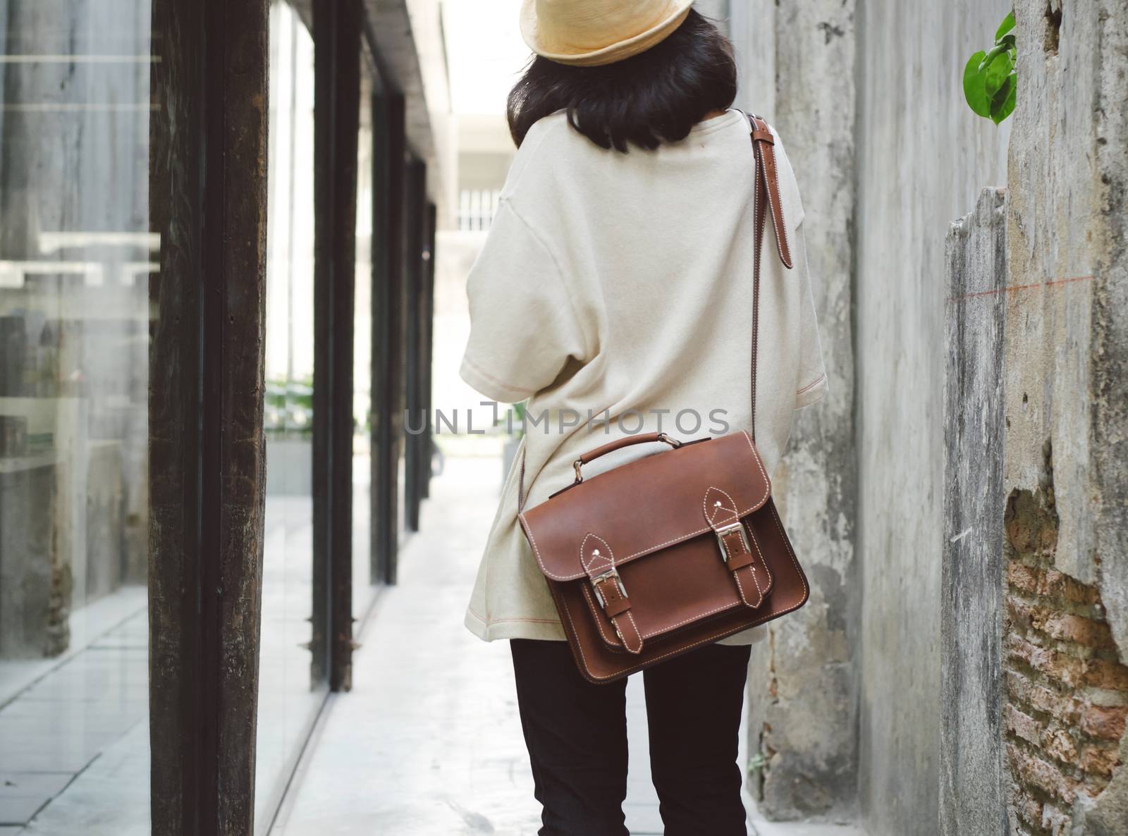 Fashion girl with leather bag at concrete alleyway by siraanamwong