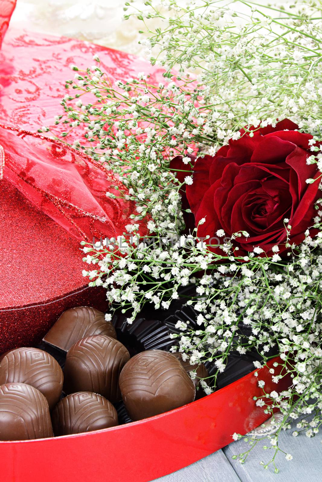 Heart shaped box of Valentines Day chocolates with beautiful long stem red roses.