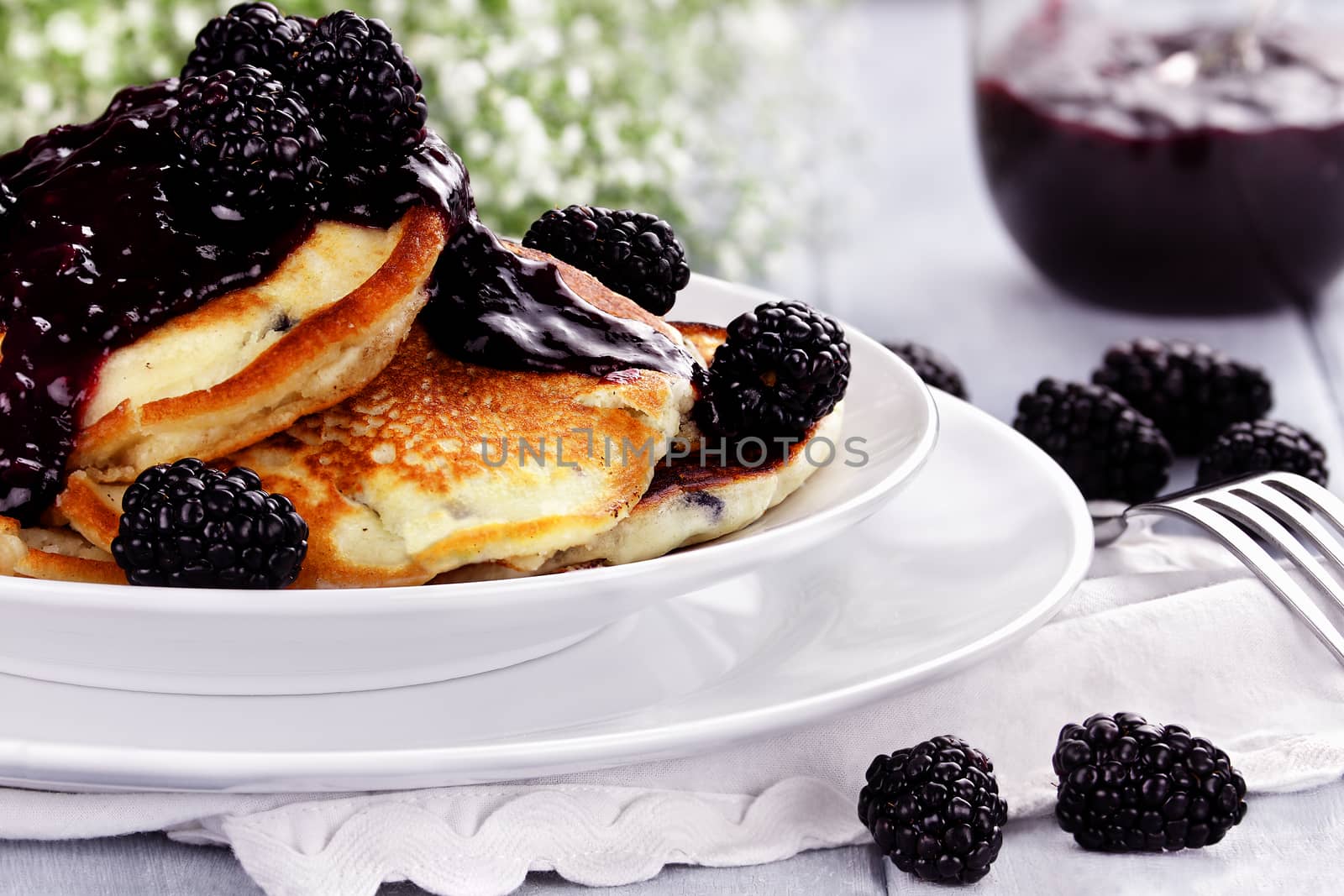 Delicious golden pancakes with fresh blackberries and blackberry jam. Extreme shallow depth of field.