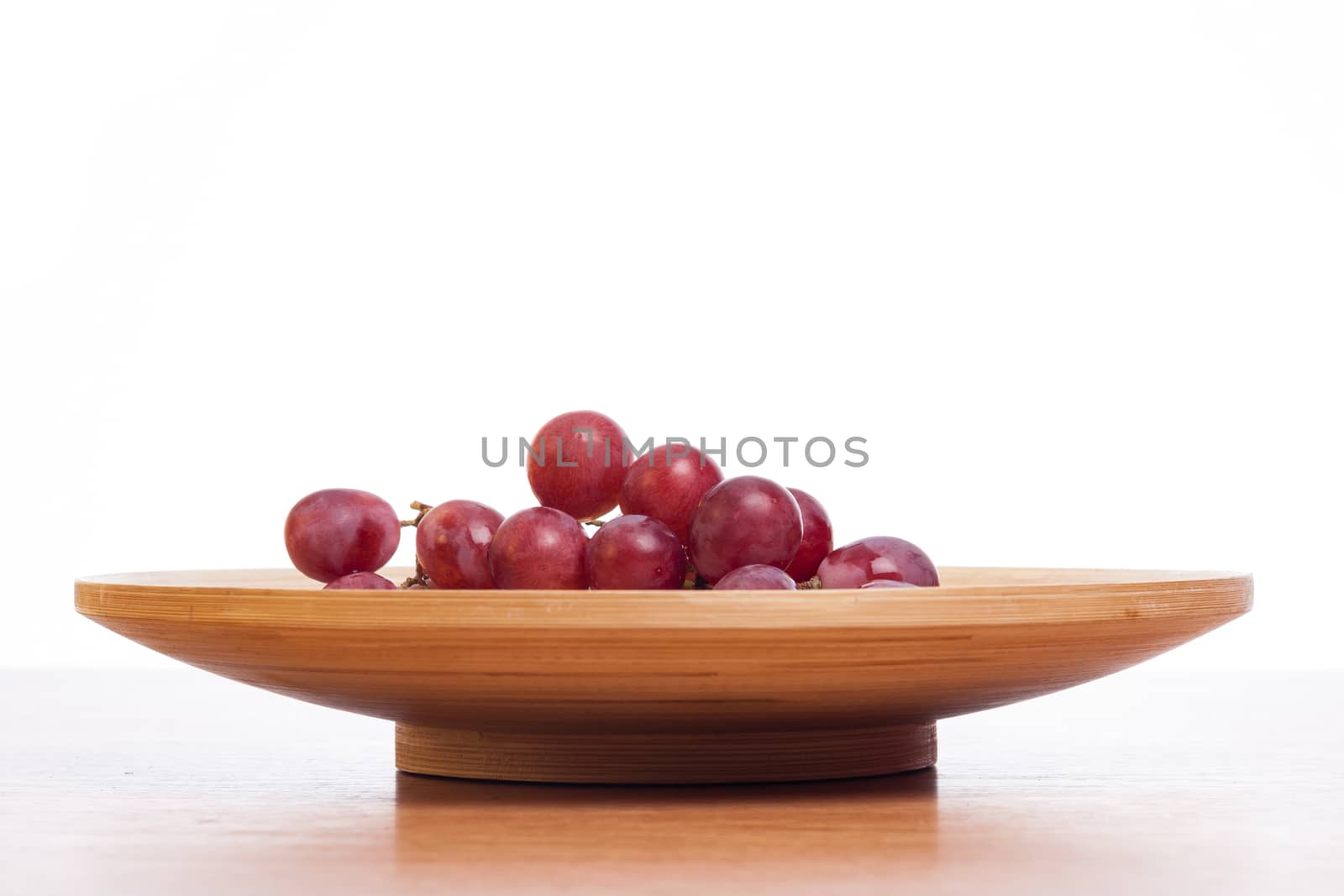 Big rose grapes on a wooden plate