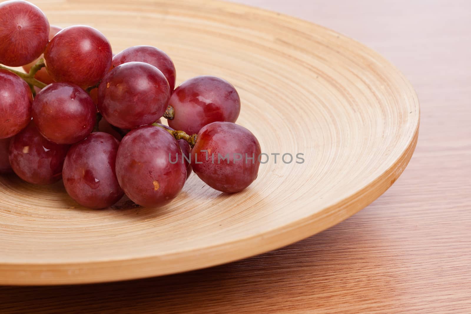 Big rose grapes on a wooden plate