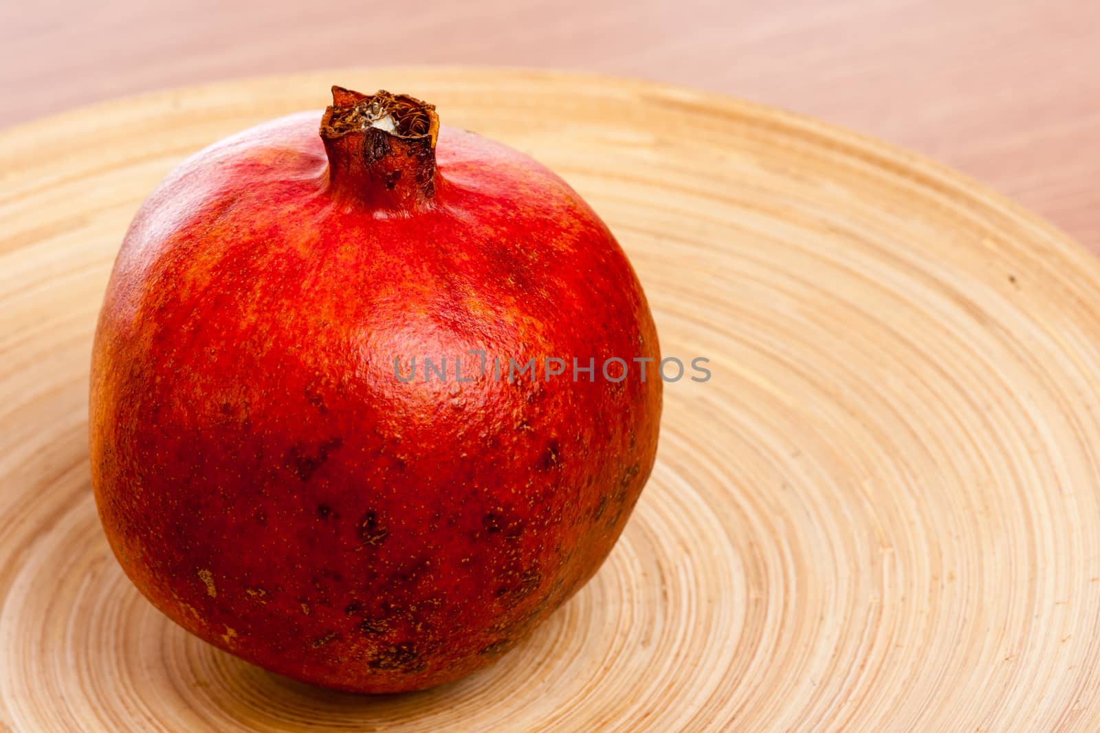 Big ripe pomegranate on a wooden plate