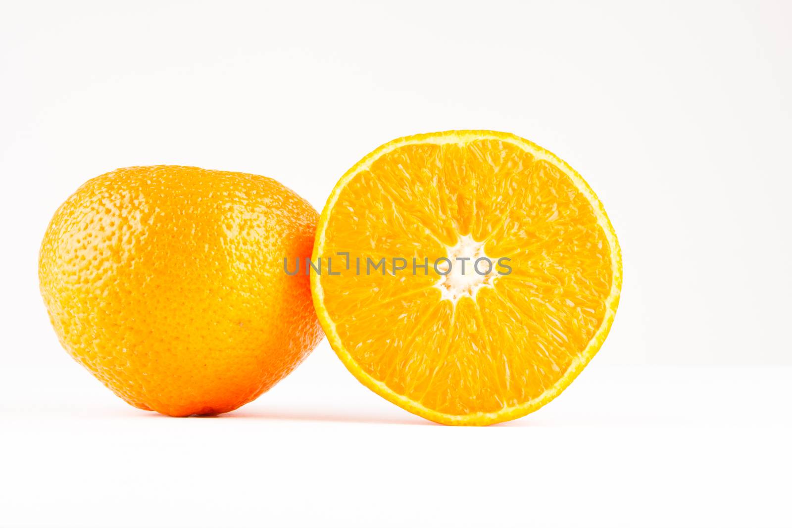 two mandarines one whole one sliced on white background