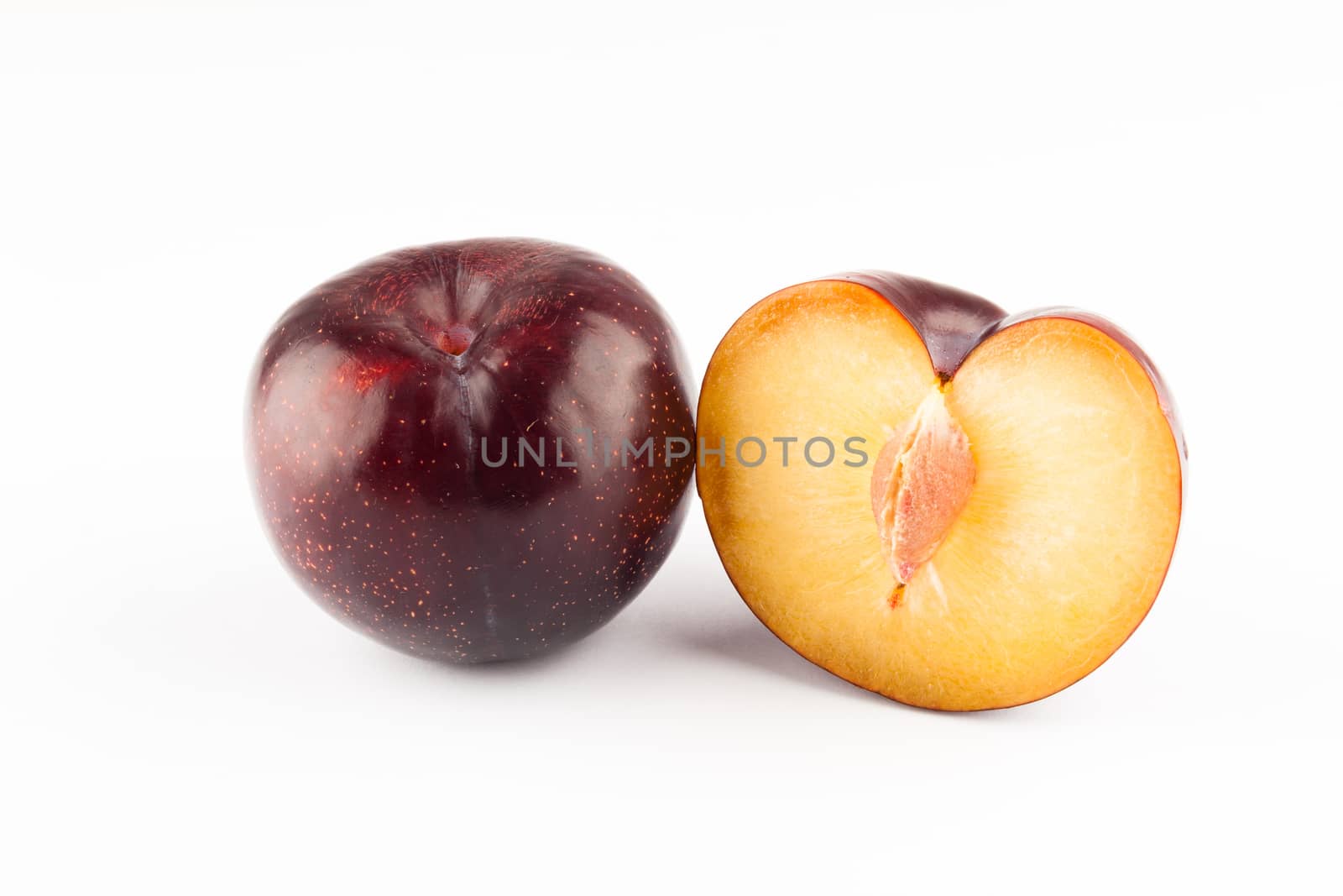 big ripe prunes closeup on white backgroud one sliced