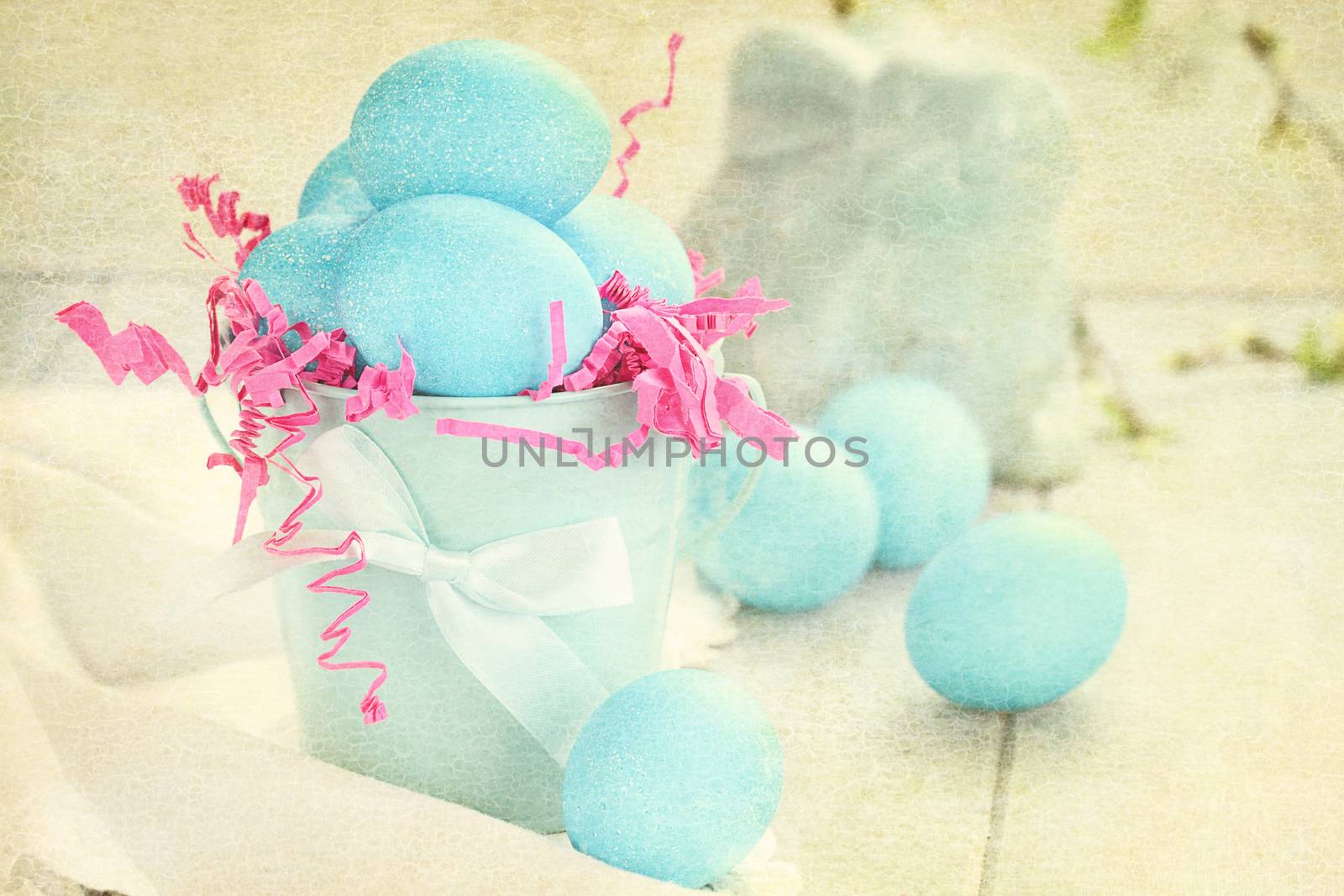 Muted textured Easter eggs in a blue tin bucket. Shallow depth of field.