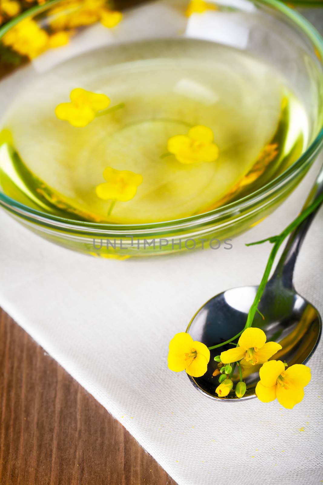 Rapeseed oil with rapeseed blossoms on table background