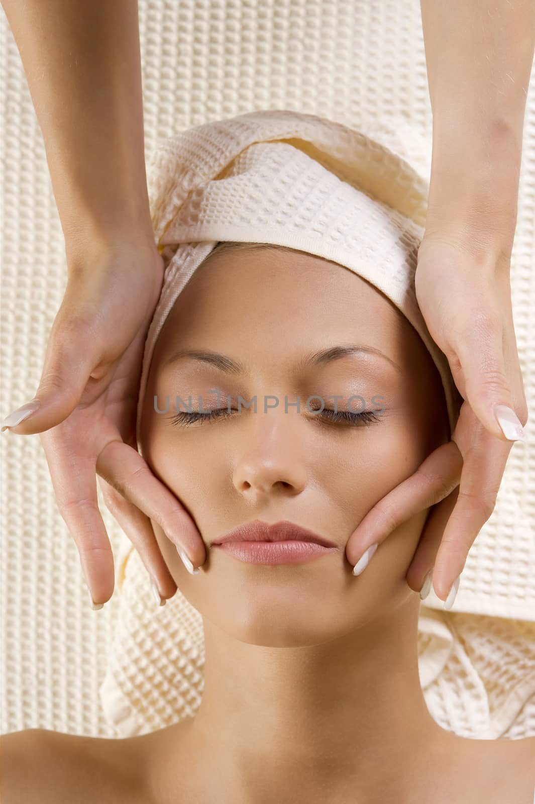 Closeup of human hands doing massage a young cute woman face