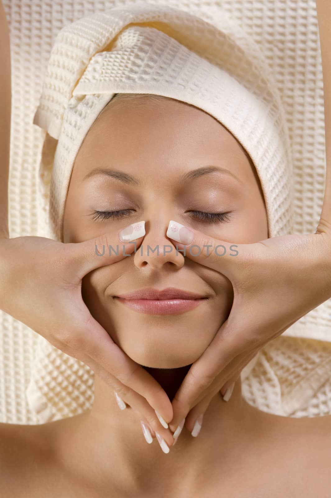 Closeup of human hands doing massage a young cute woman face