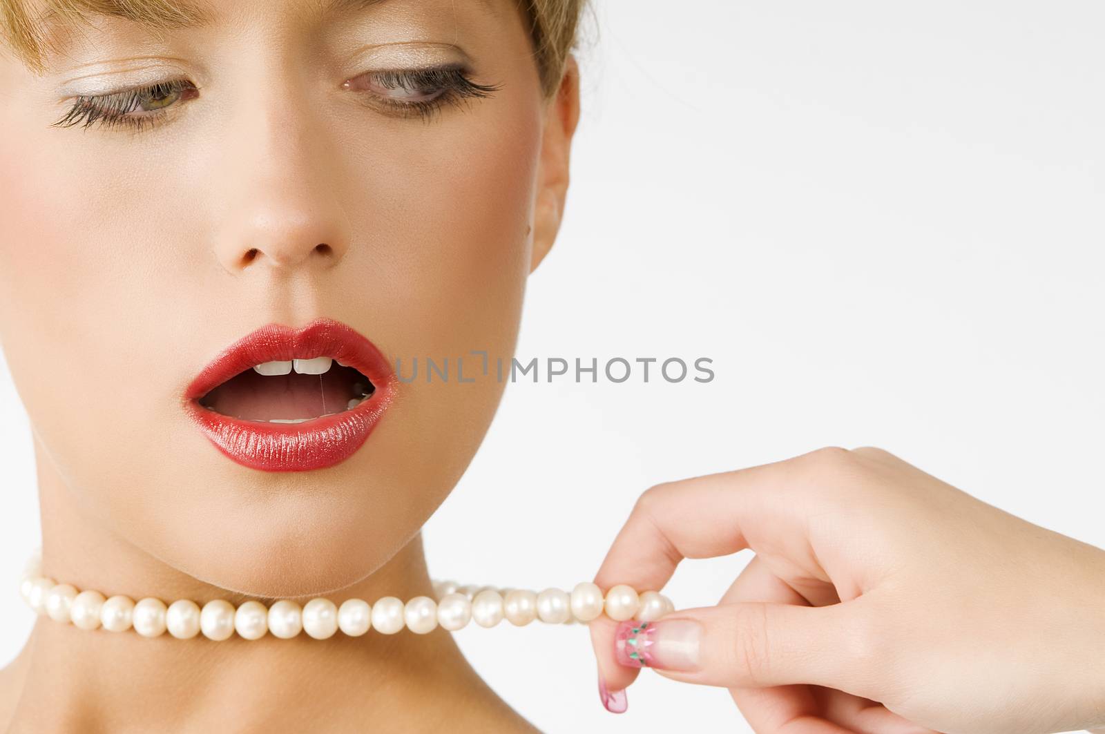 portrait of a cute girl with red lips and pearls necklace pulling by one hand