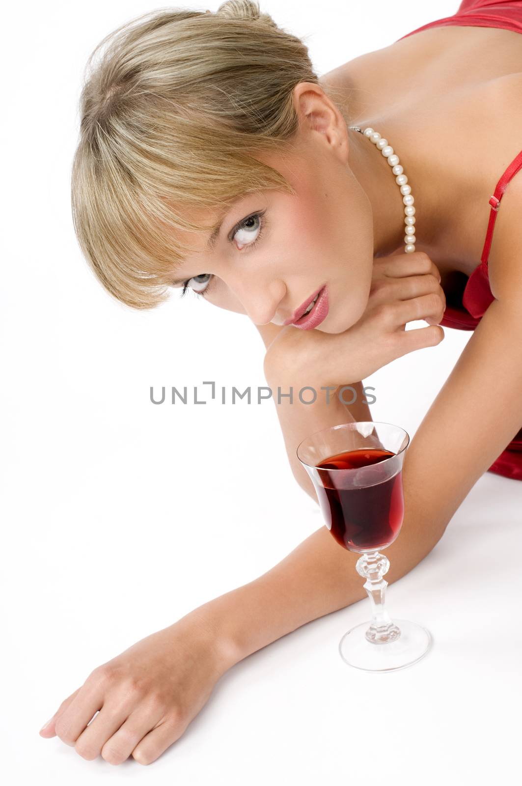 blond girl with necklace laying down on the floor near a glass of red wine