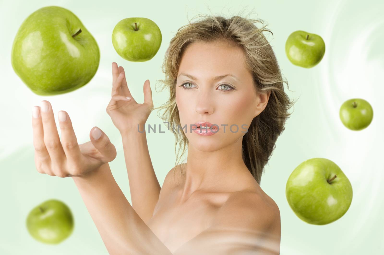 blond pretty girl trying to catch some green apple flying all around her
