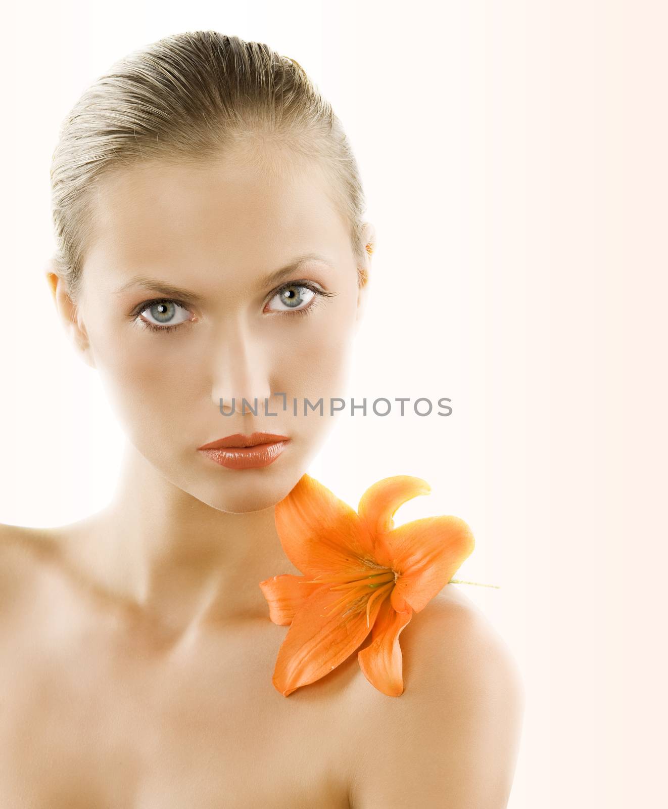 great portrait of a blond girl with wet hair and an orange lily on her shoulder