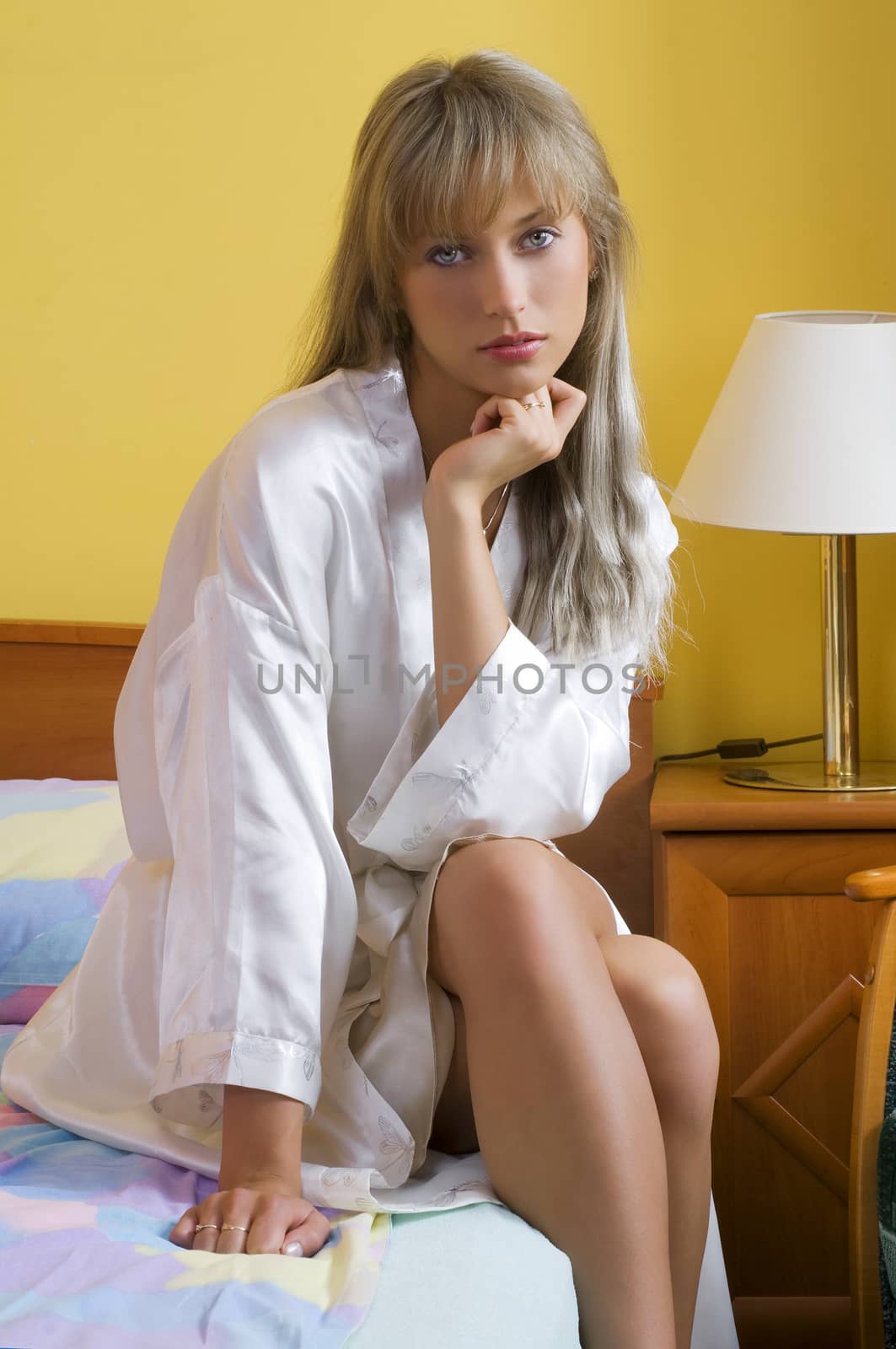 cute blond woman in nightgown sitting on the border bed looking in you