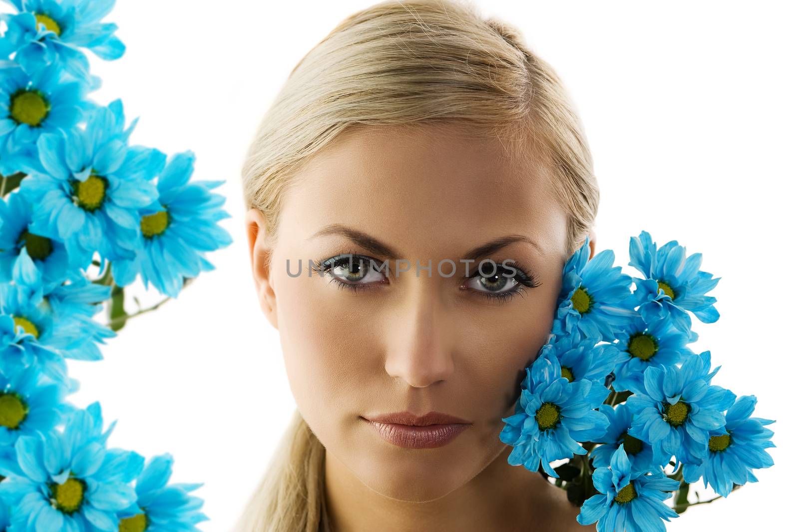 close up of a young blond woman with blue daisy near face