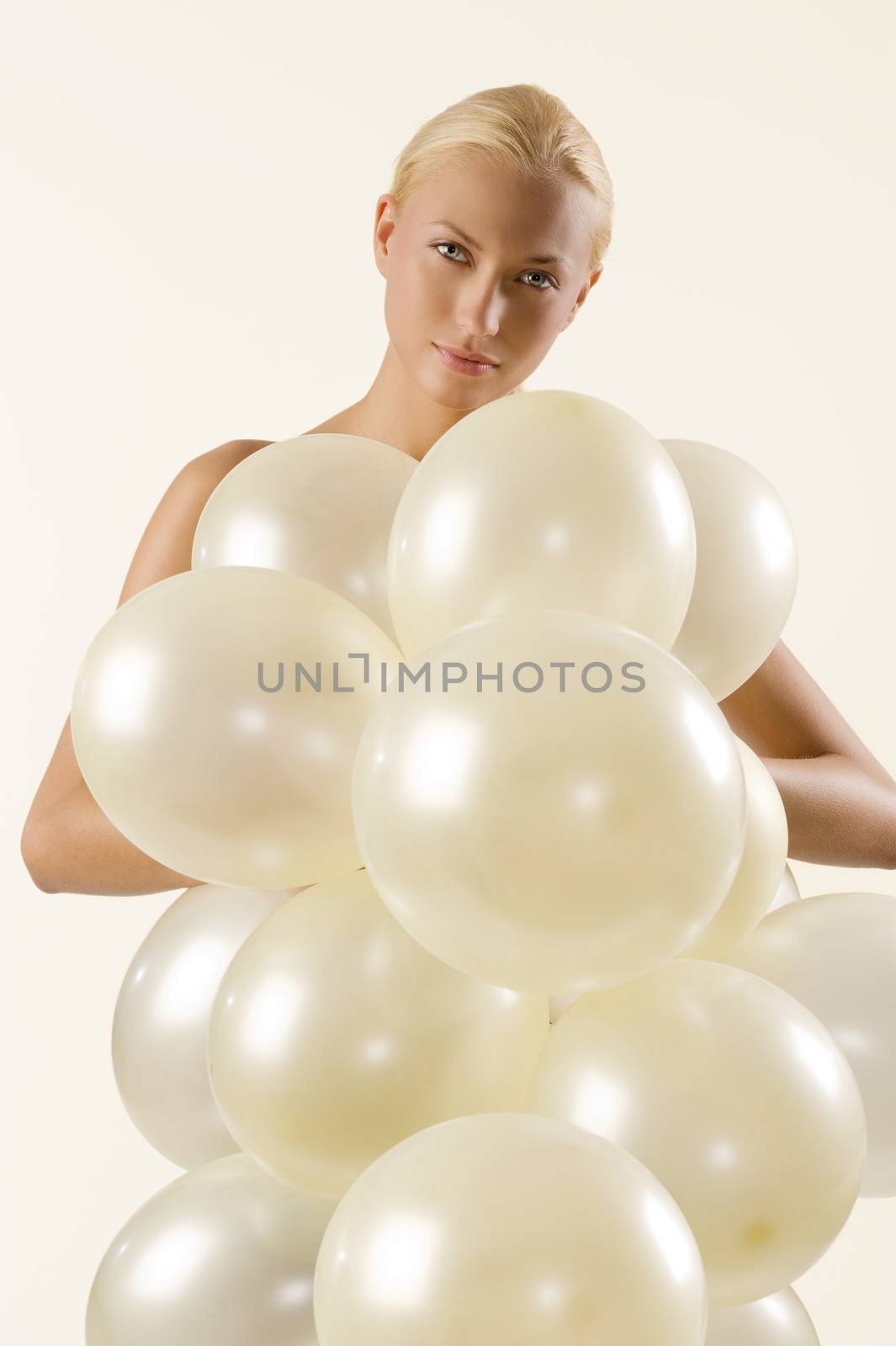 beautiful blond woman playing and covering her body with white balloons