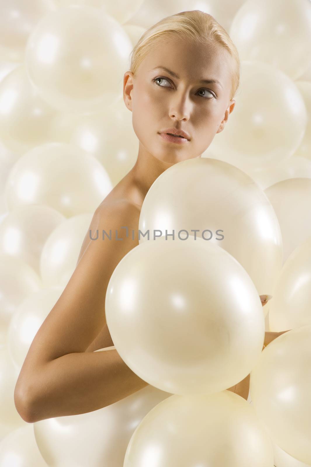 studio shot portrait os beautiful blond woman covering her body with white balloons