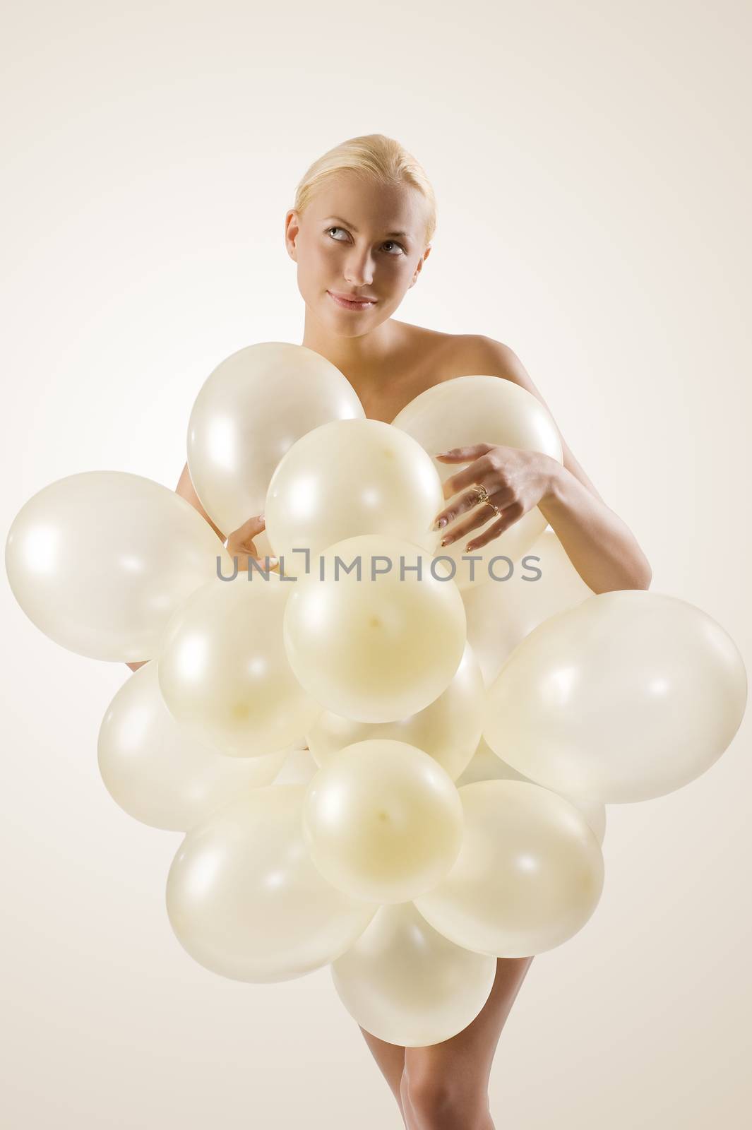 beautiful blond woman playing and covering her body with white balloons