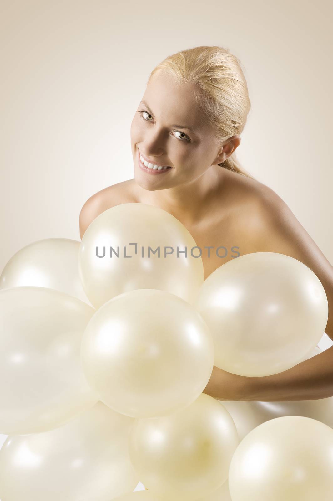 cute blond girl arming some air balloons looking in camera smiling