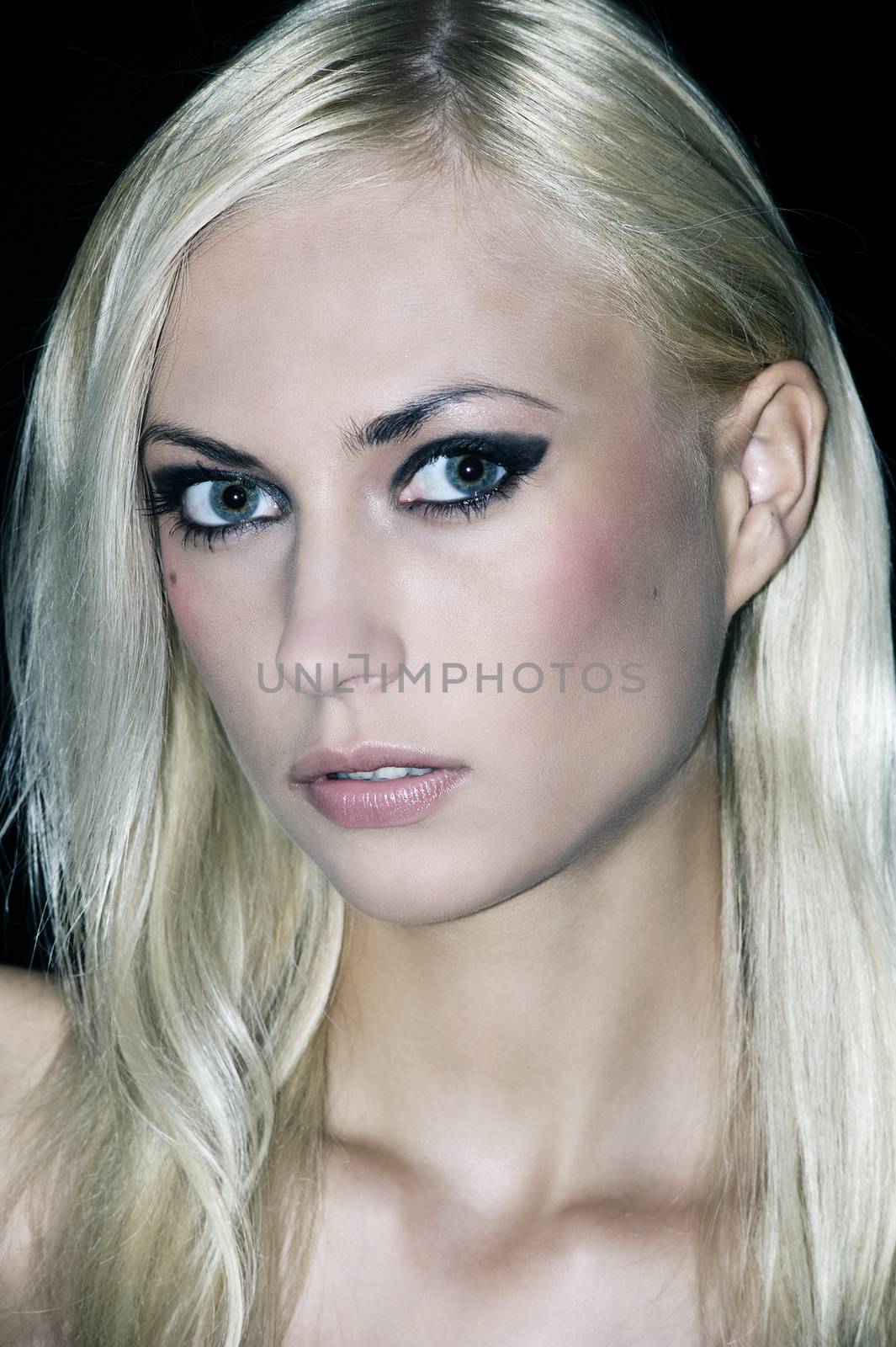 portrait with only the camera light of a nice blond looking in camera with strong make up