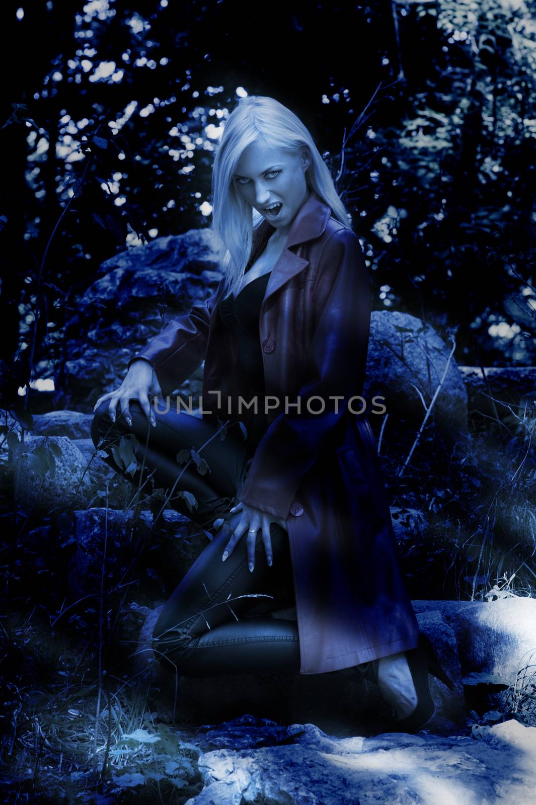 blond sexy woman outside in park looking like a vampire during th night