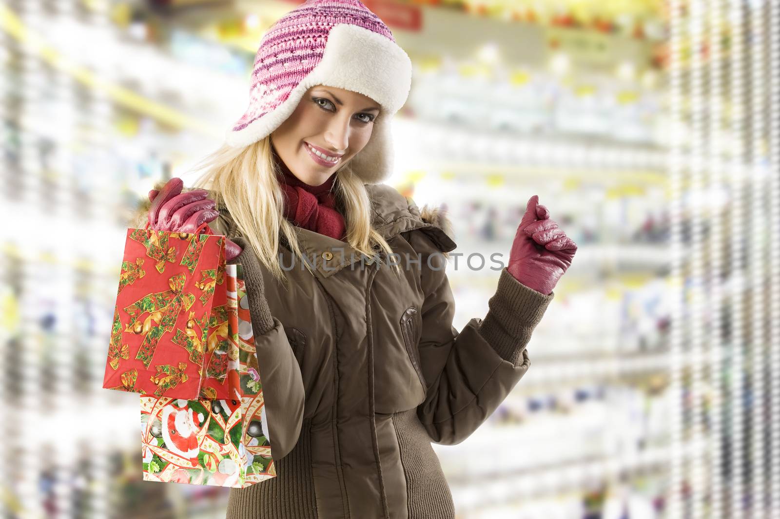 very cute blond girl in winter dress with hat and gloves and shopping christmas bag