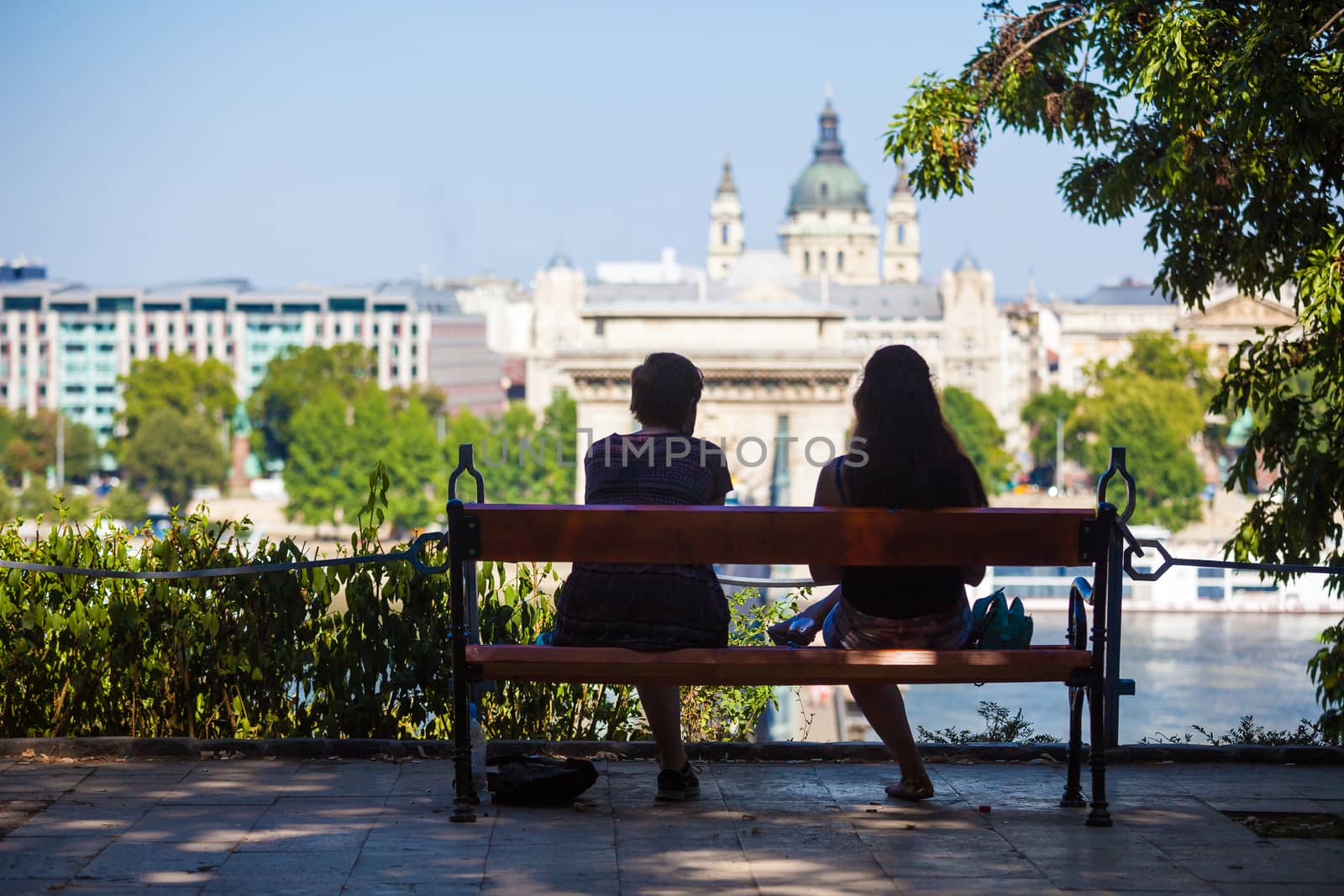 BUDAPEST, HUNGARY - AUGUST 2: Two girls on a bench watching at Szechenyi Chain Bridge on August 2, 2013 in Budapest.