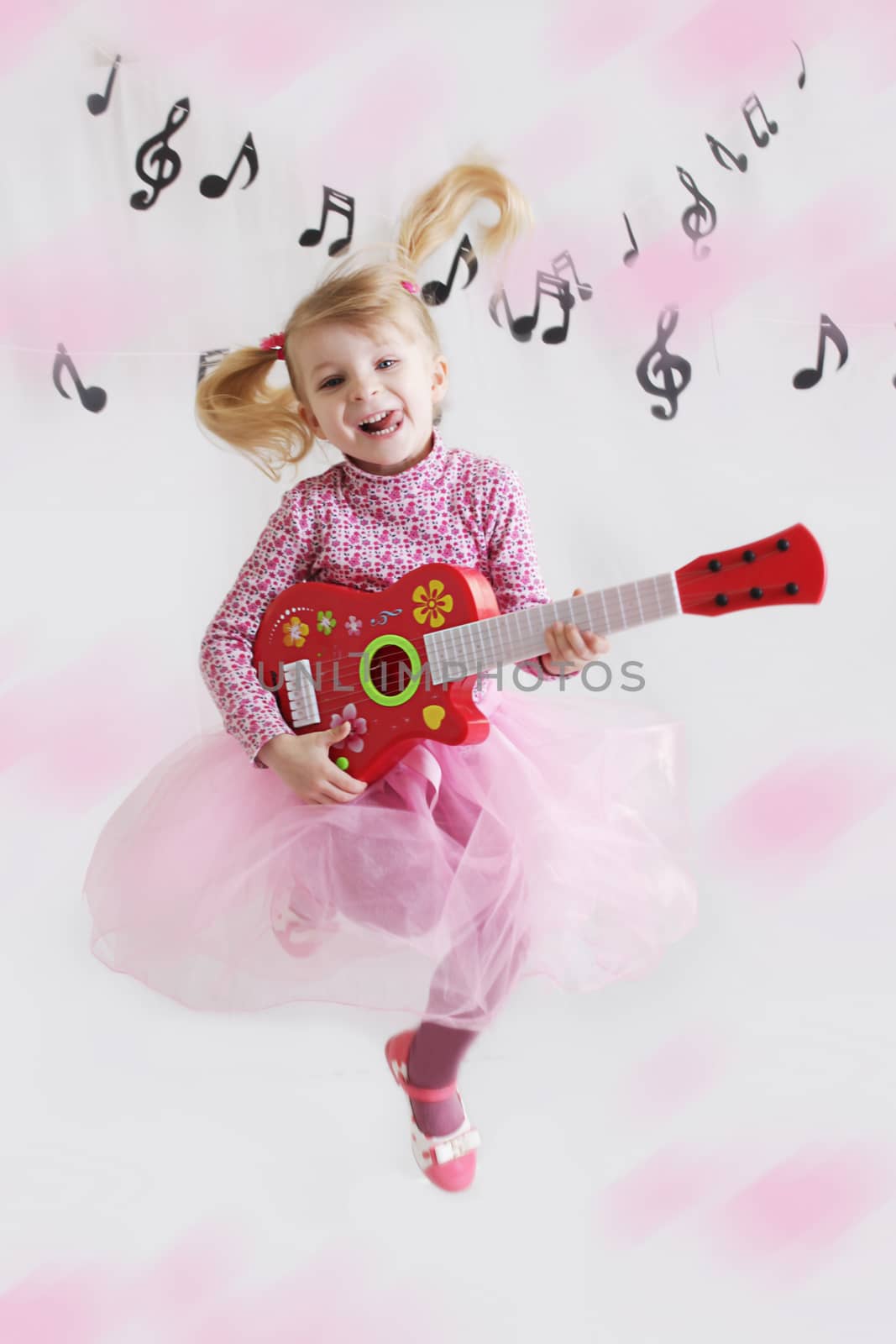 Joyful girl with guitar on music notes background