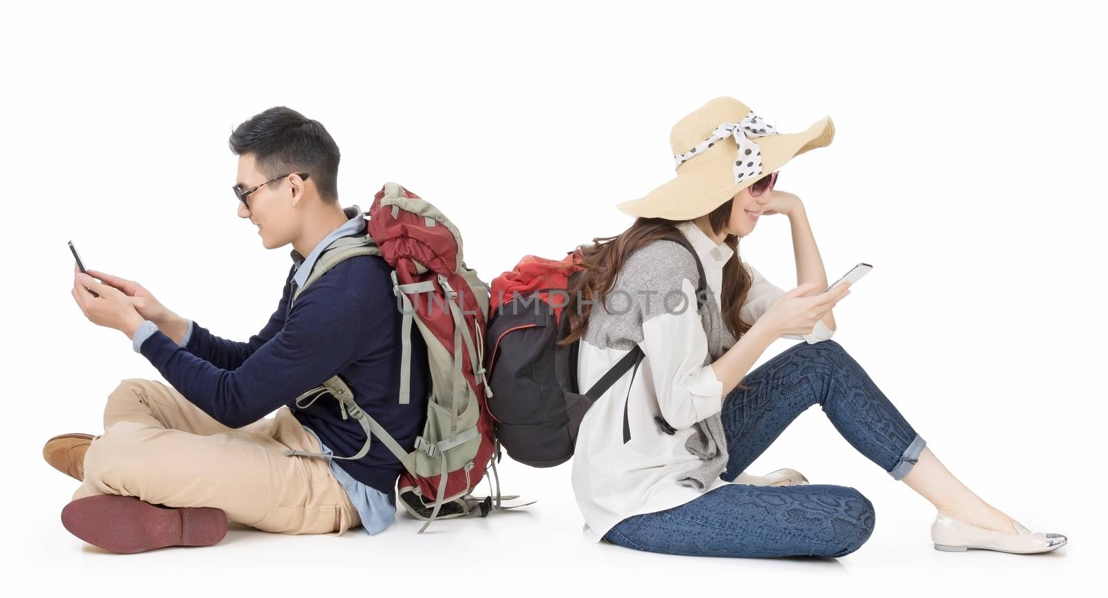 Asian young couple traveling and sitting on ground back to back and using mobile phone, full length portrait on white background.